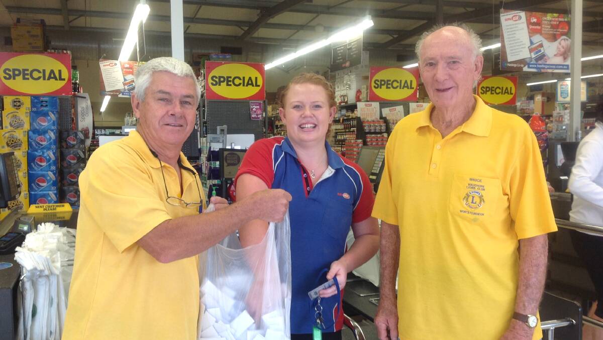Lions Greg Cavanagh and Bruce Cant help IGA retail assistant Georgia Malcolm to draw the winning ticket at the IGA store on October 10.