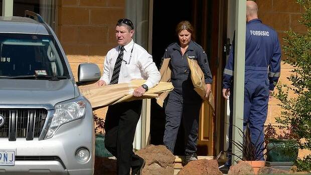 Detectives and forensic officers carrying evidence from the victim's house. Photo: Justin McManus