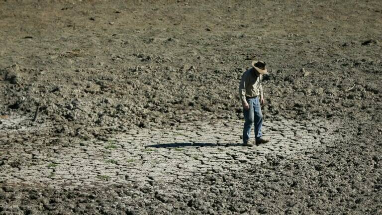 A farmer on an empty dam on his property in Gundy in the Hunter region of NSW. 
