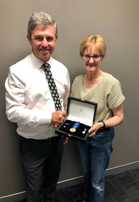 Lyne MP Dr David Gillespie presents Denise McCarthy with a replica of the stolen OAM awarded to her late father, Dr Keith Beck.