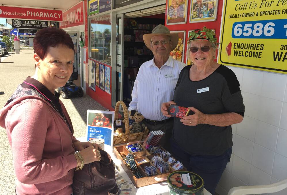 SUPPORTING VETERANS: Trish Kelman contributes to Legacy Week by buying from the Wauchope stall run by volunteers Colin and Fay Stidworthy.