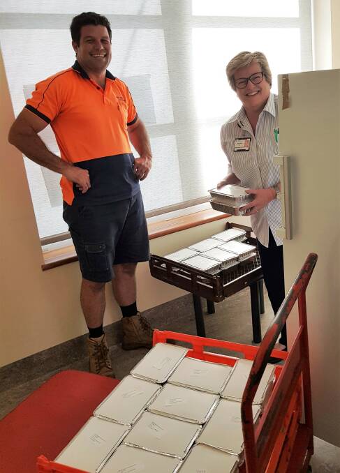 Team effort: Josh Slade receives a helping hand from patient flow nurse manager Sandy Lee to unpack the donated family meals. Photo: supplied