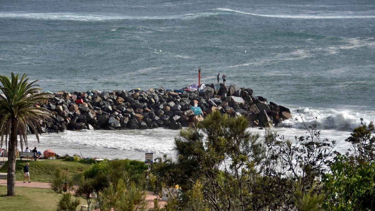 High tide: The swell at Town Beach reaches the dunes as people a the end of the break wall watch the conditions. Photo: Matt Attard